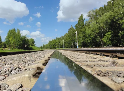 Milled rail with gravel, meadow, trees and blue skies in the background