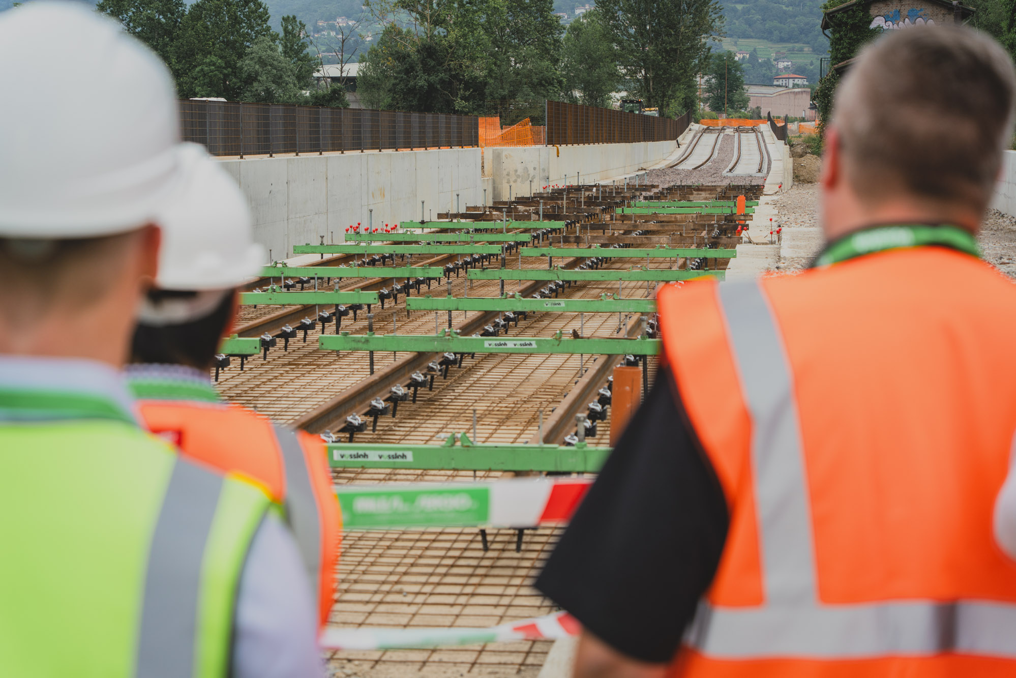 Vossloh employees in safety vests and helmets inspecting a track under construction with installed rail fastenings