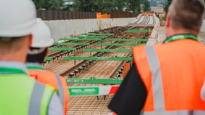 Vossloh employees in safety vests and helmets inspecting a track under construction with installed rail fastenings