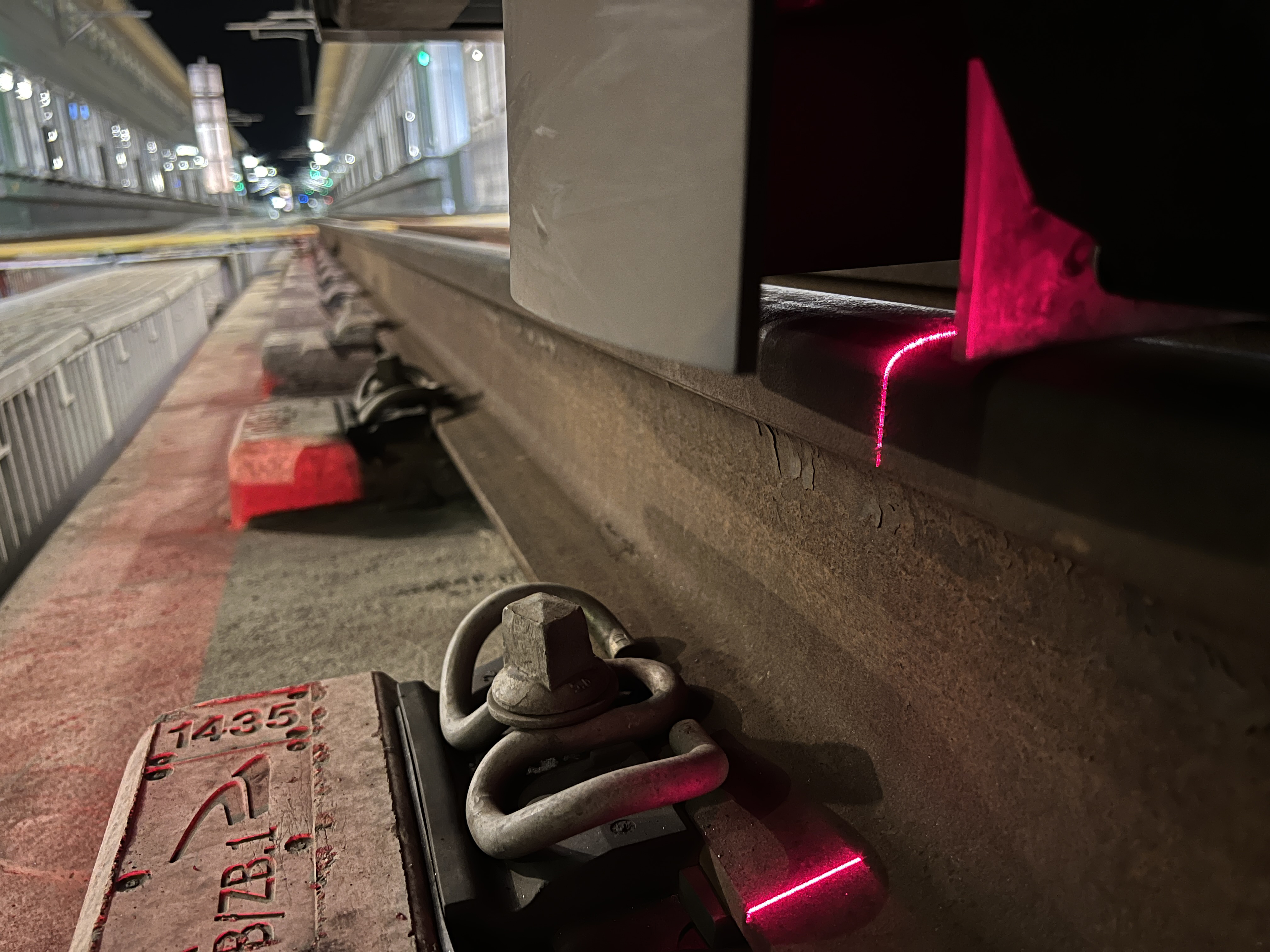 Close-up of a rail and fastening with red laser lines for track measurement in the context of Vossloh connect.