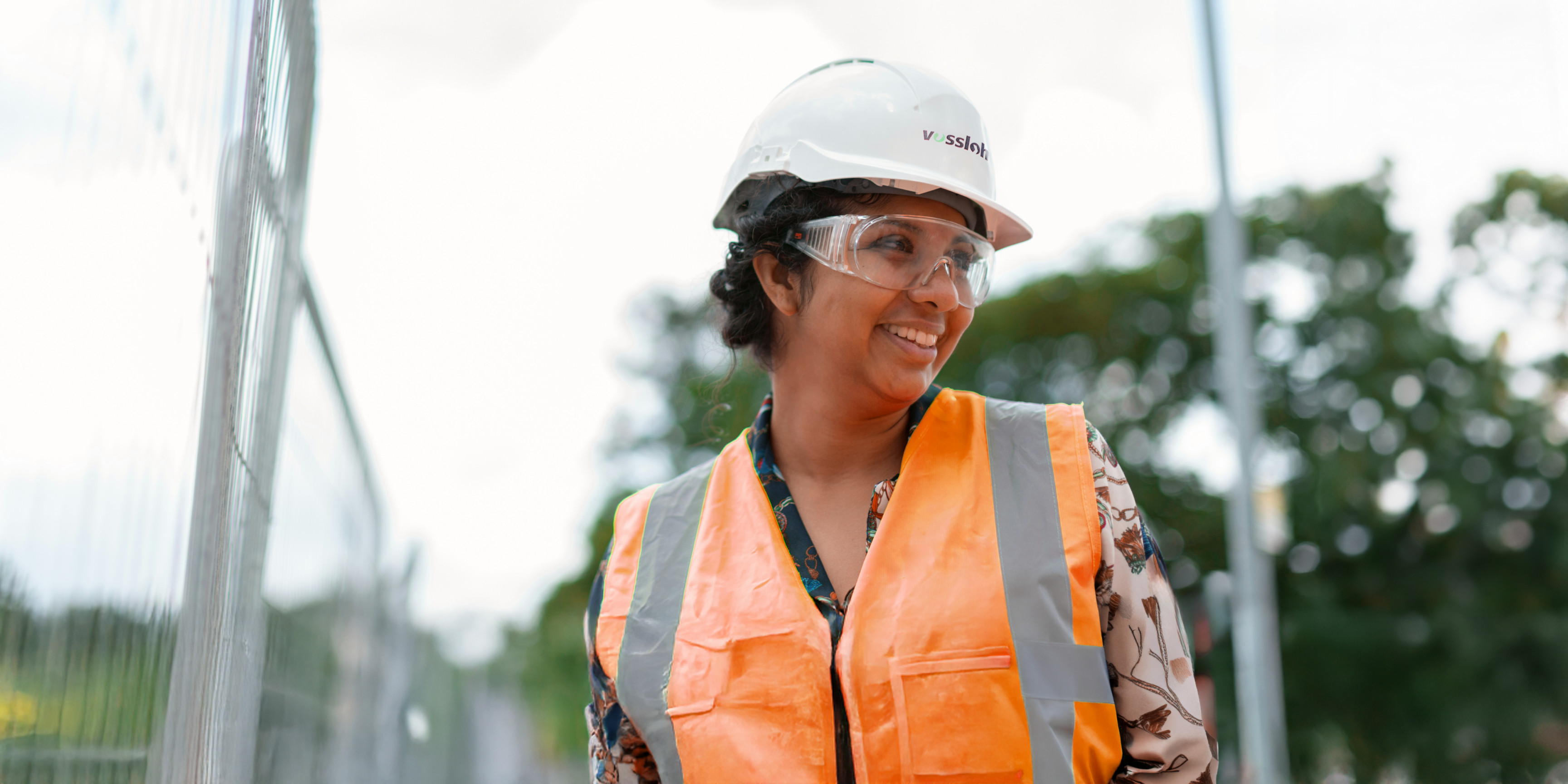 Smiling woman with work helmet and safety vest